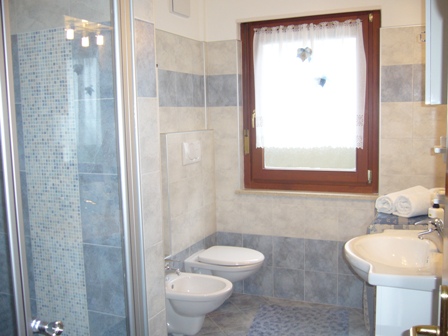 bagno con doccia, water, bidet, lavandino con specchio e lavatrice.