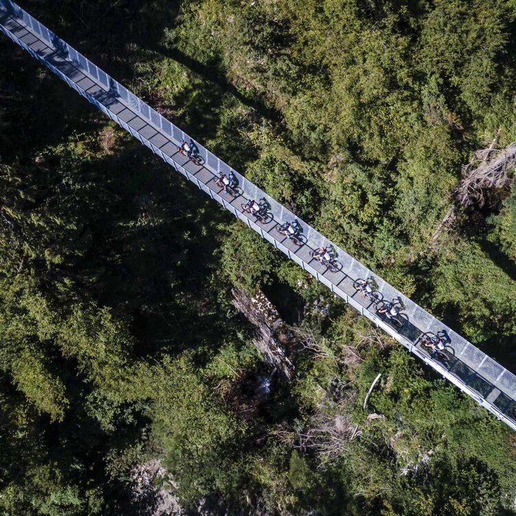 Gruppo di bikers in un ponte sospeso in primiero