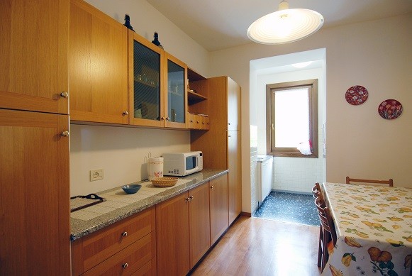 sullo sfondo il cucinino con piano cottura a induzione, forno, lavastoviglie